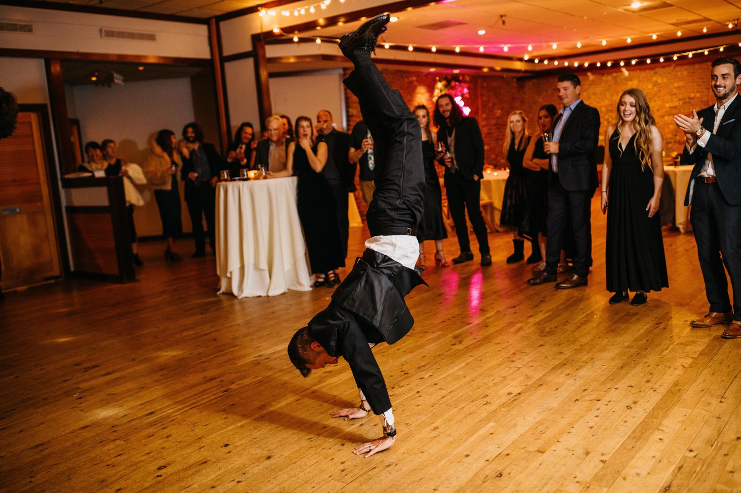 groom doing handstand at wedding reception